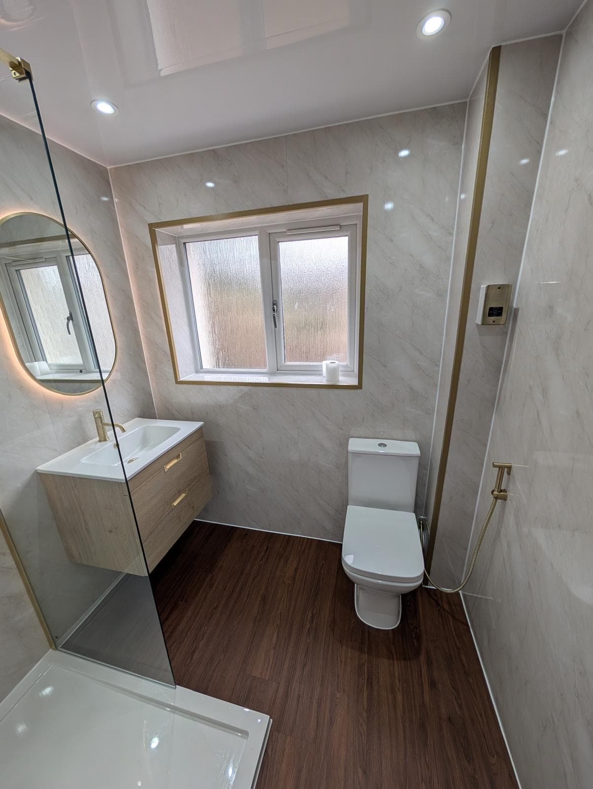 Marble-effect bathroom with brushed brass fittings, fitted by First Plumb Solutions